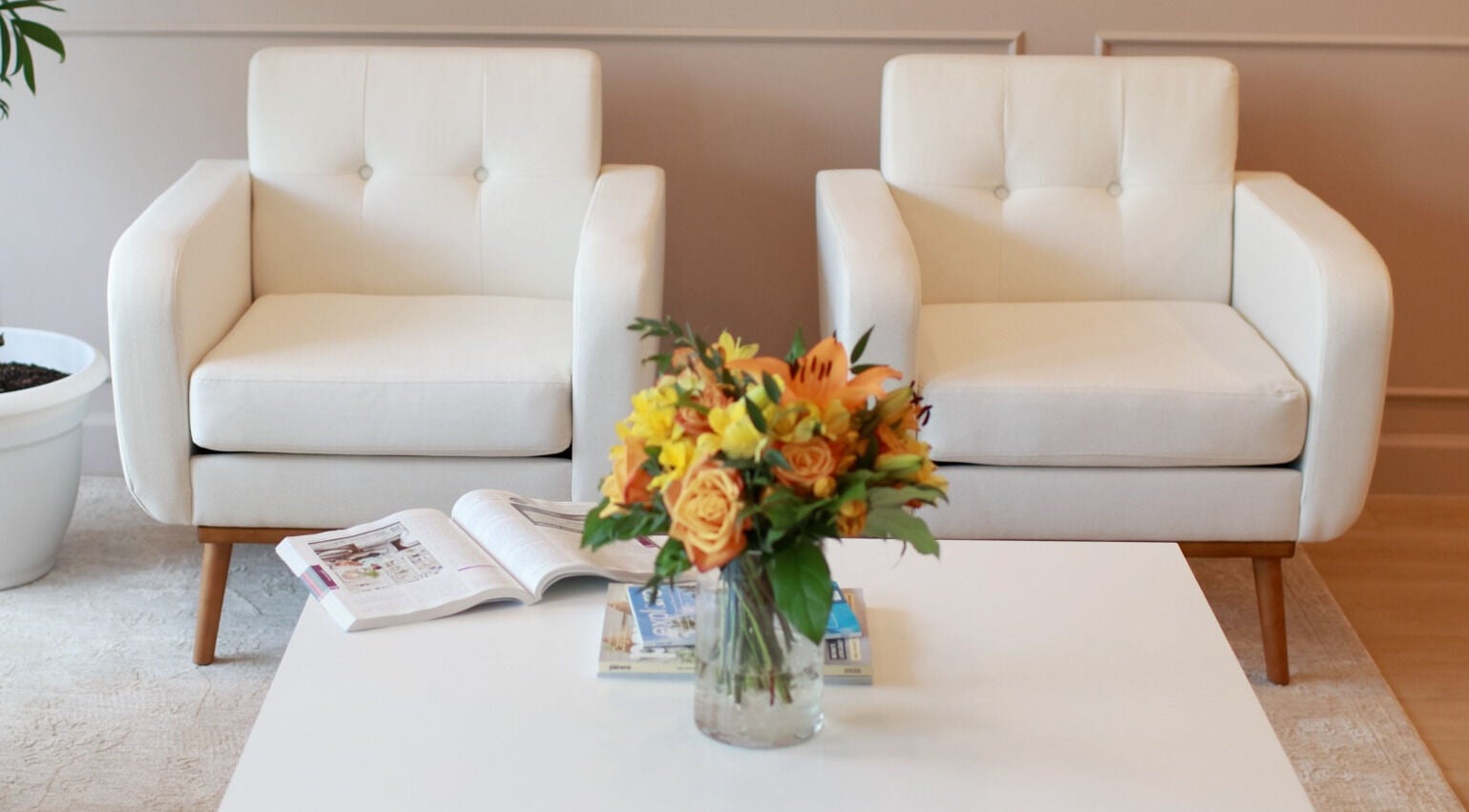 Relaxing seating area at Detox Spa in Georgetown, KY, featuring white armchairs and a floral arrangement.