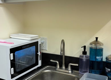 Clean sink area at One Drop Studio, Arcadia, California, US with sanitation supplies and a sterilizer.