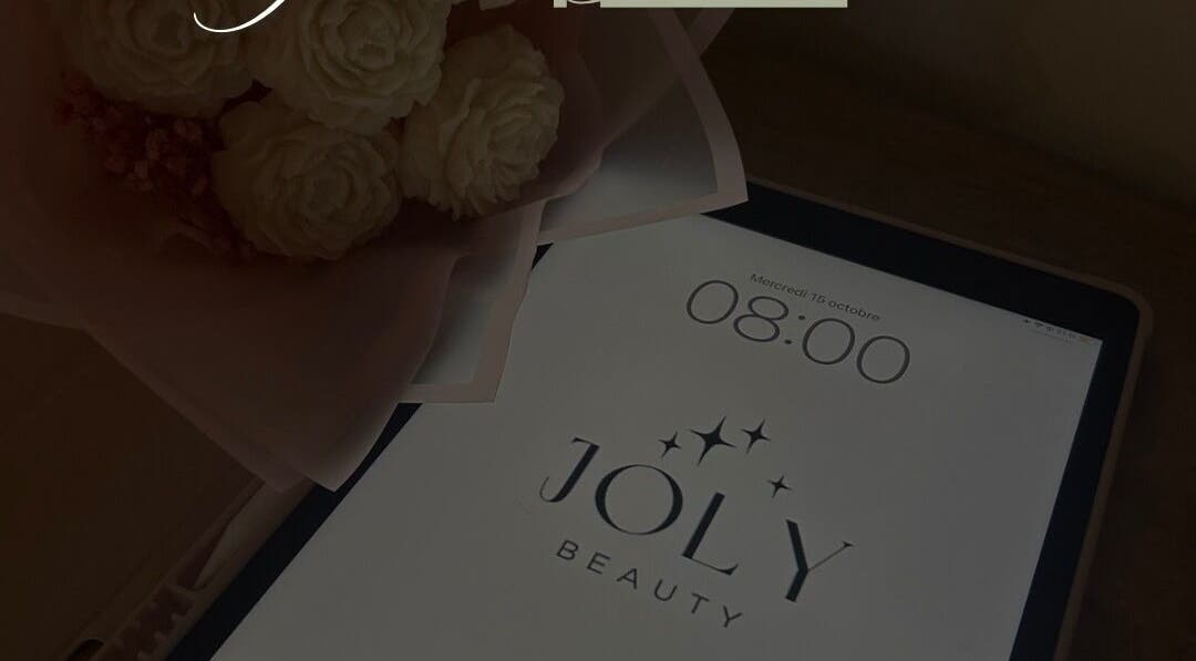 Tablette avec le logo JOLY BEAUTY à Meussia, Bourgogne-franche-comté, FR, à côté d'un bouquet de fleurs.