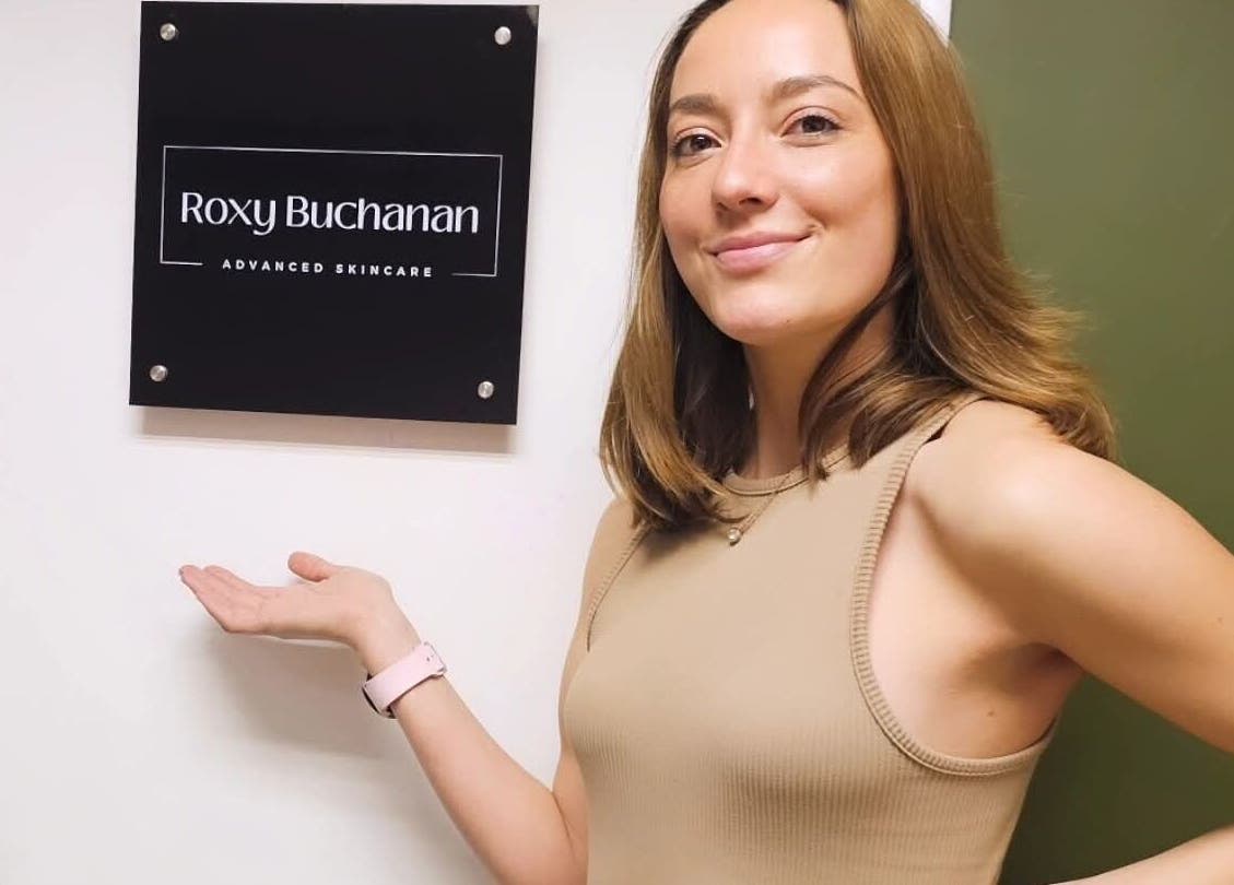 Smiling woman pointing at Roxy Buchanan sign at Kloof, Dr. Nicolette, Kloof, Kwazulu-natal, ZA.