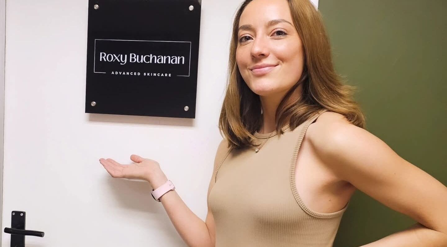 Smiling woman pointing at Roxy Buchanan sign at Kloof, Dr. Nicolette, Kloof, Kwazulu-natal, ZA.