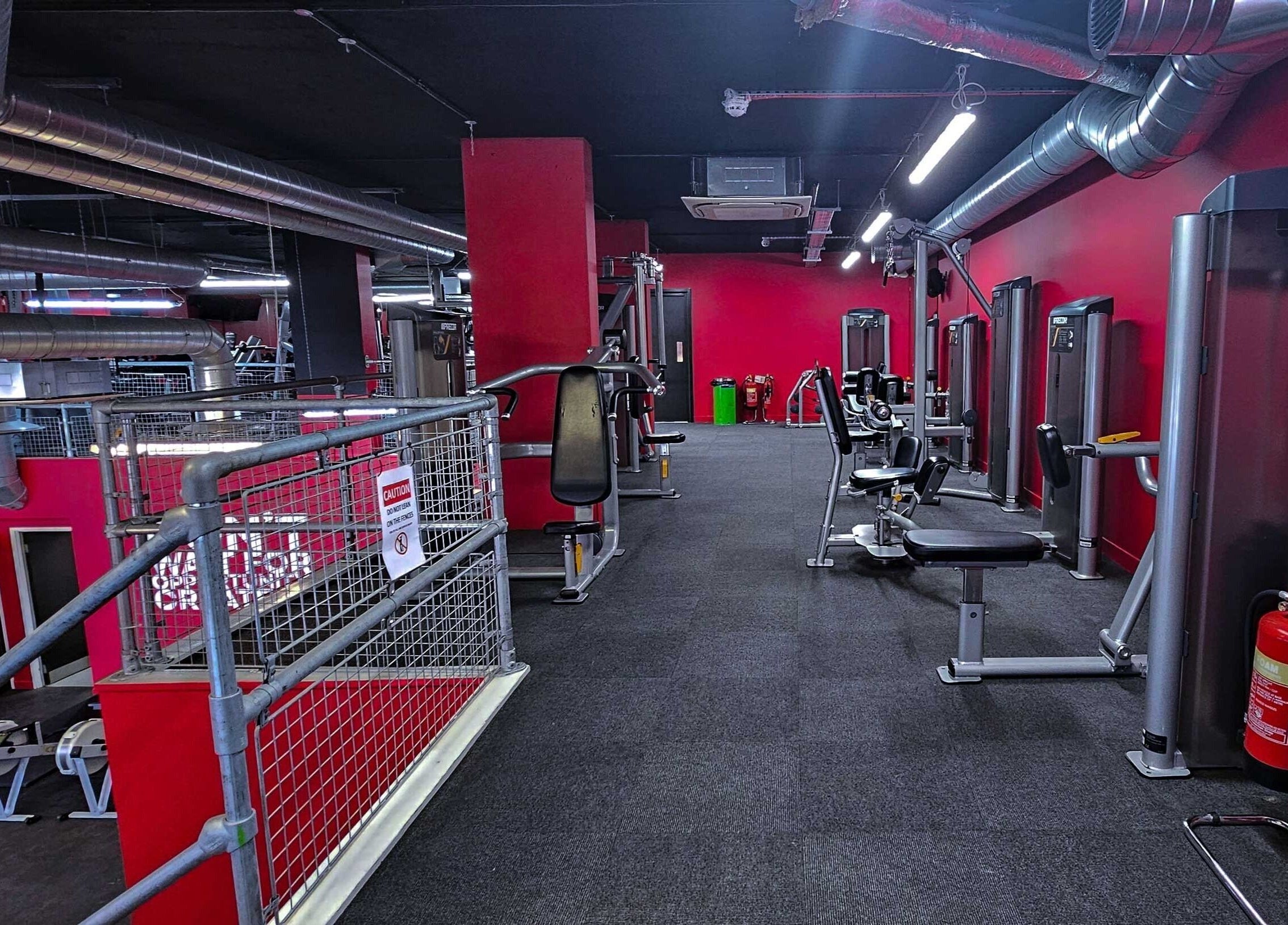 Modern fitness equipment at Wembley Fitness, Wembley, England, GB, featuring bold red and black decor.