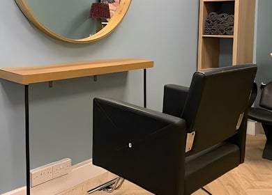 Modern salon chair and mirror at Jolie Hairdressing in London, England, GB, offering stylish haircuts.