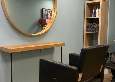 Cozy hairdressing station at Jolie Hairdressing, London, England, GB featuring a stylish mirror and chair.
