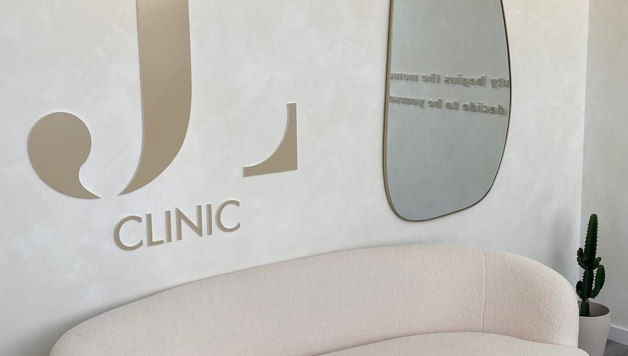Sala de espera elegante no JL CLINIC, Linda-a-velha, Lisboa, PT, com sofá e espelho moderno.