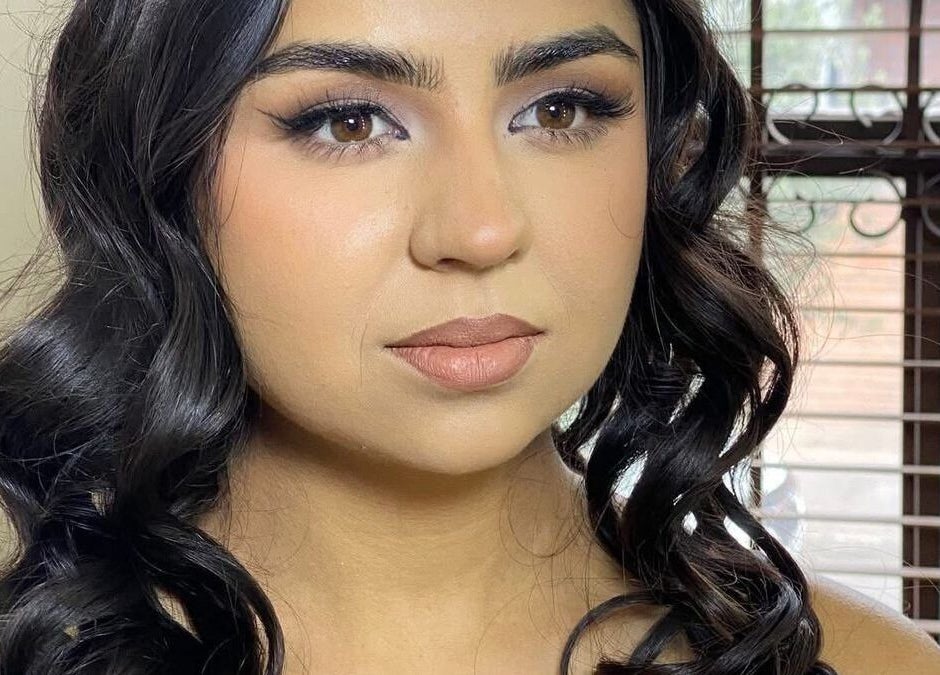 Cliente con rizos elegantes en KIM STUDIO, Juan Aldama, Chihuahua, MX, mostrando un maquillaje impecable.