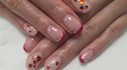 Heart-accented nail art at Tokyo Nailya, London, England, GB, featuring shiny red tips and gems.