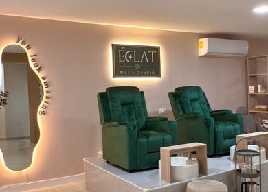 Acogedor interior de ECLAT Nails Studio en Panamá con sillas verdes y espejo iluminado.