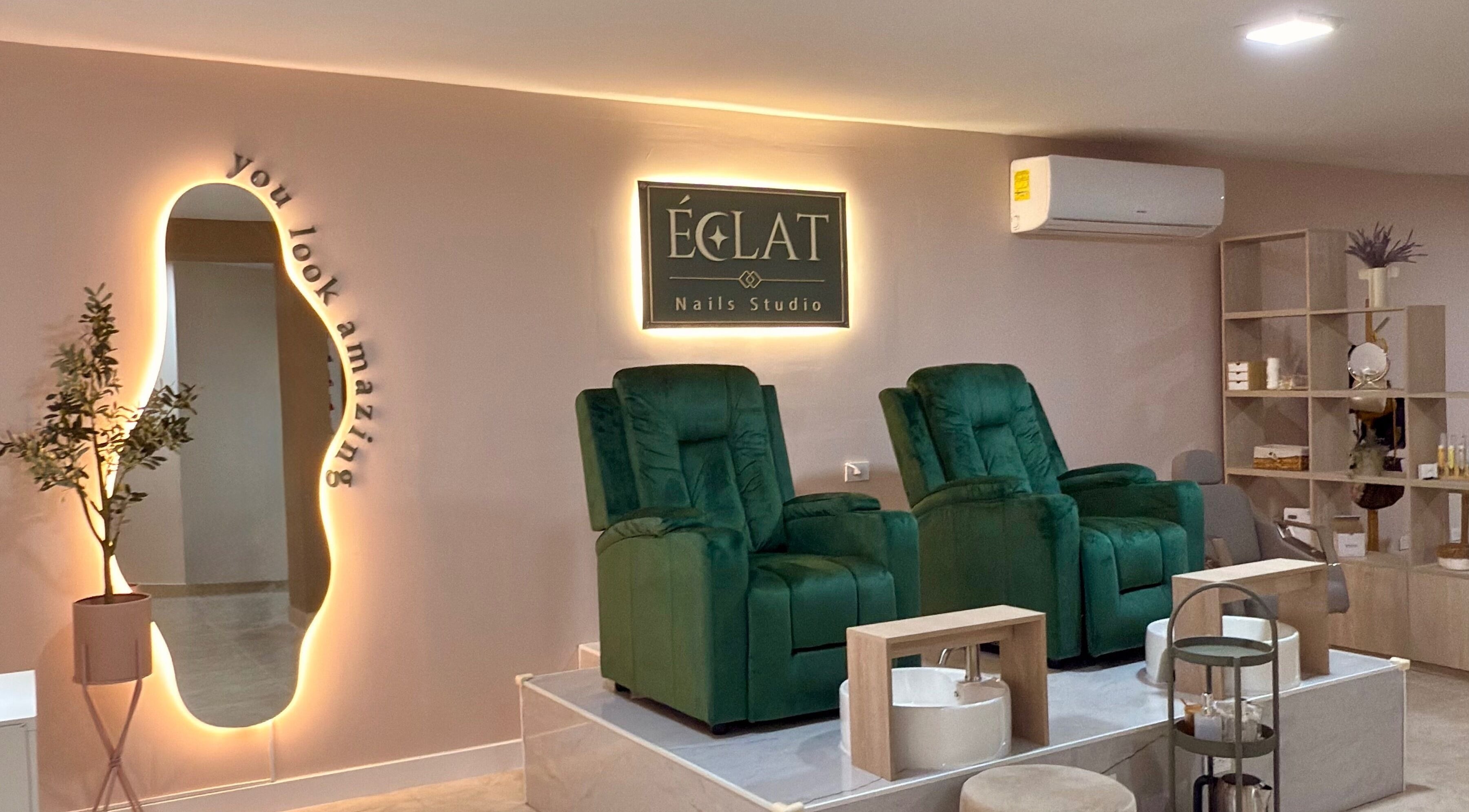 Acogedor interior de ECLAT Nails Studio en Panamá con sillas verdes y espejo iluminado.