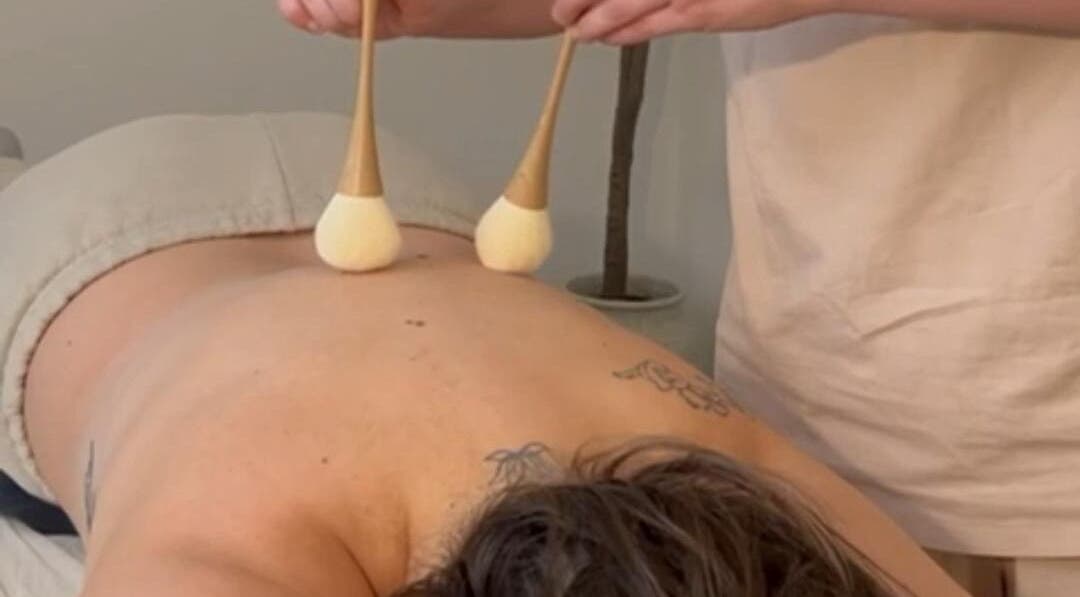 Back massage session at The Light Room, GB. Using soft brushes for a relaxing wellness experience.