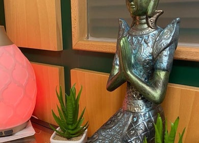 Estatua en Samy Therapy Zone, A Coruña, ES, junto a lámpara y plantas crean ambiente relajante.