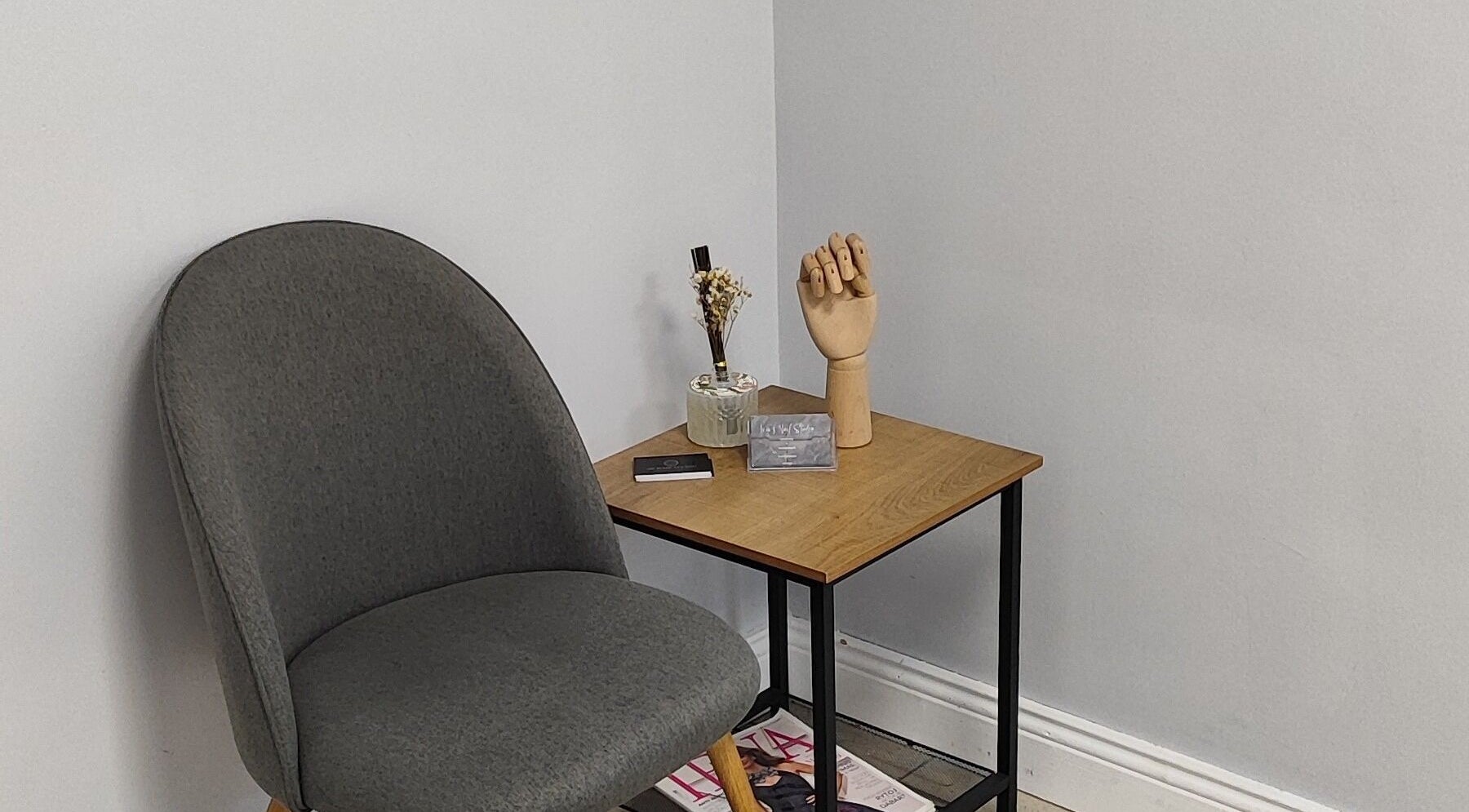 Cozy corner at Ieva's Nail Studio in Claregalway, IE featuring a gray chair and wooden decor.