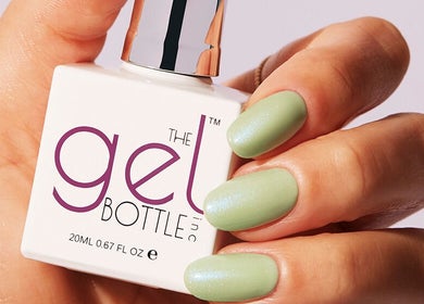 Close-up of a hand with mint green gel nails holding polish bottle at I J Beauty By Lauren, St Helens, England, GB.