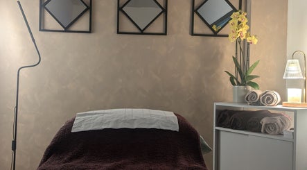 Tranquil treatment room at I J Beauty By Lauren, St Helens, England, GB, with orchid and rolled towels.
