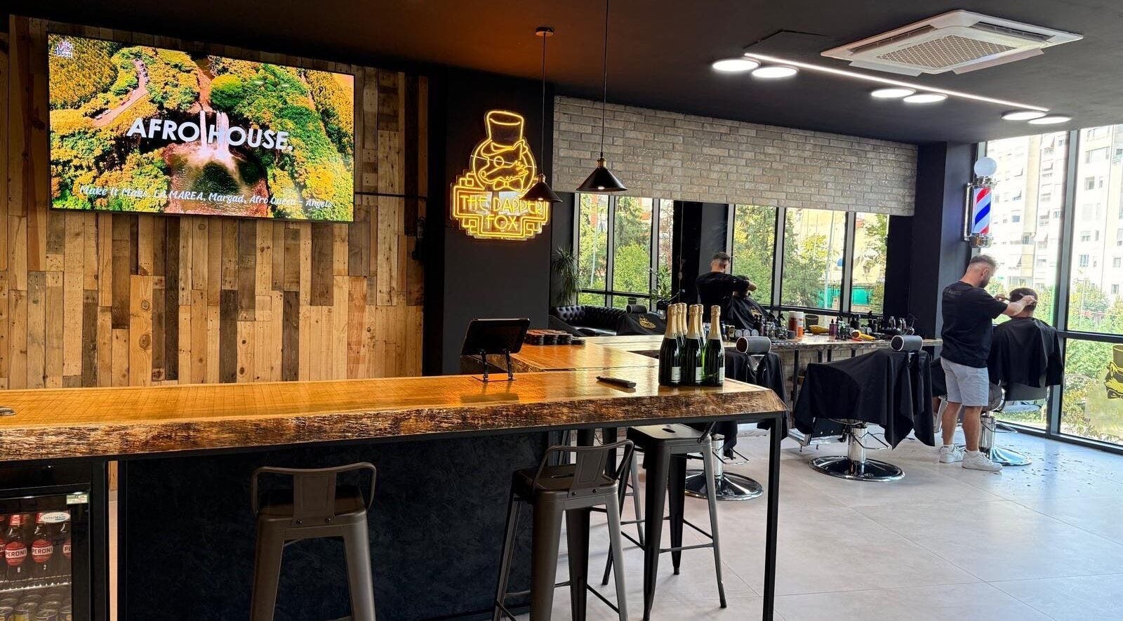 The Dapper Fox Barber in Tiranë, Tirana County, AL showcases a chic interior with a rustic bar and modern styling chairs.