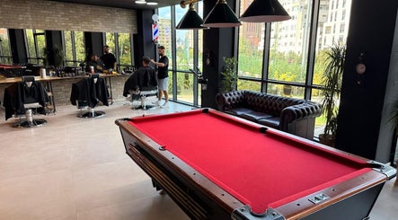 Spacious interior of The Dapper Fox Barber in Tiranë featuring a pool table and barber chairs.