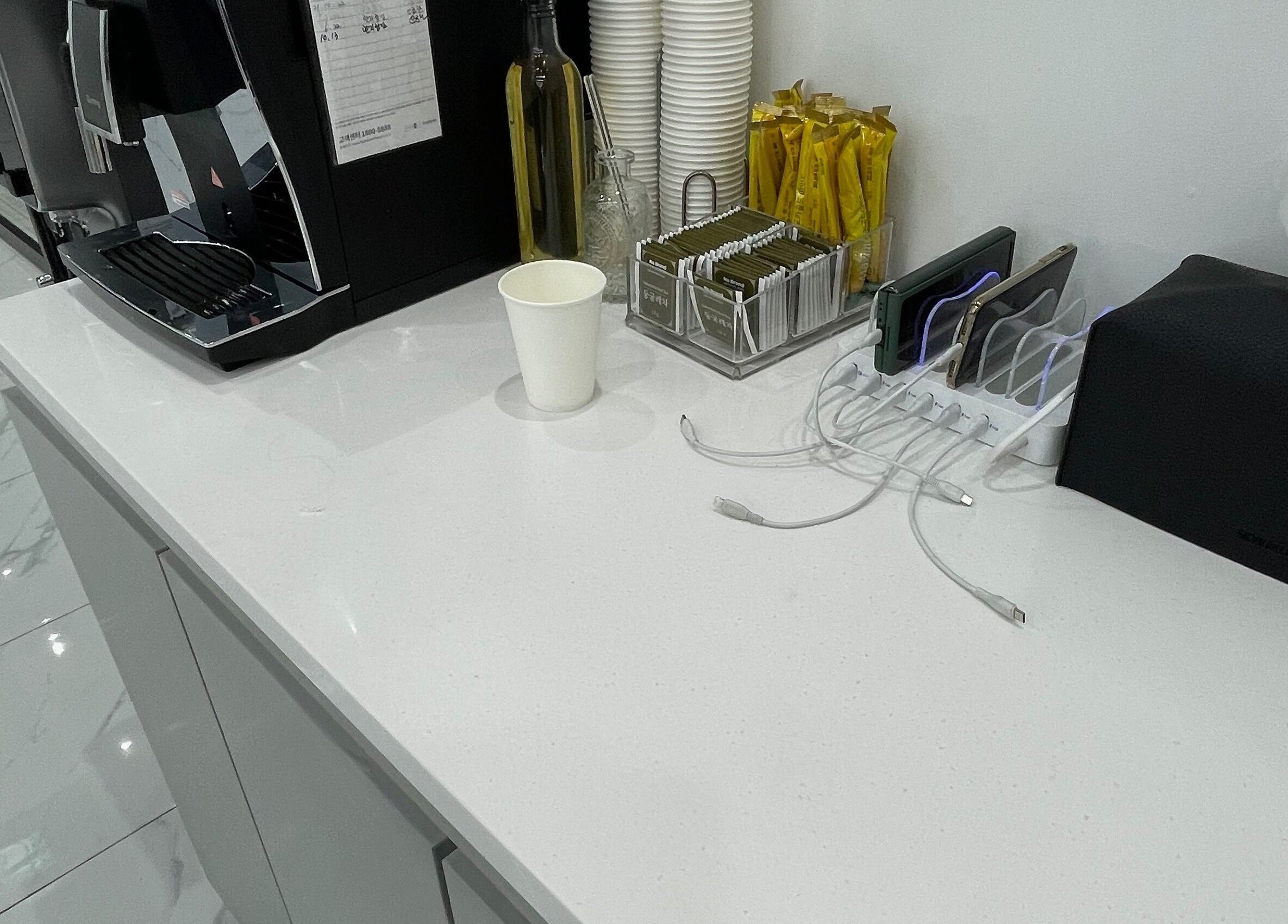 Sleek refreshment station at urGlow, Seoul, Seoul, KR with coffee setup and phone charging.