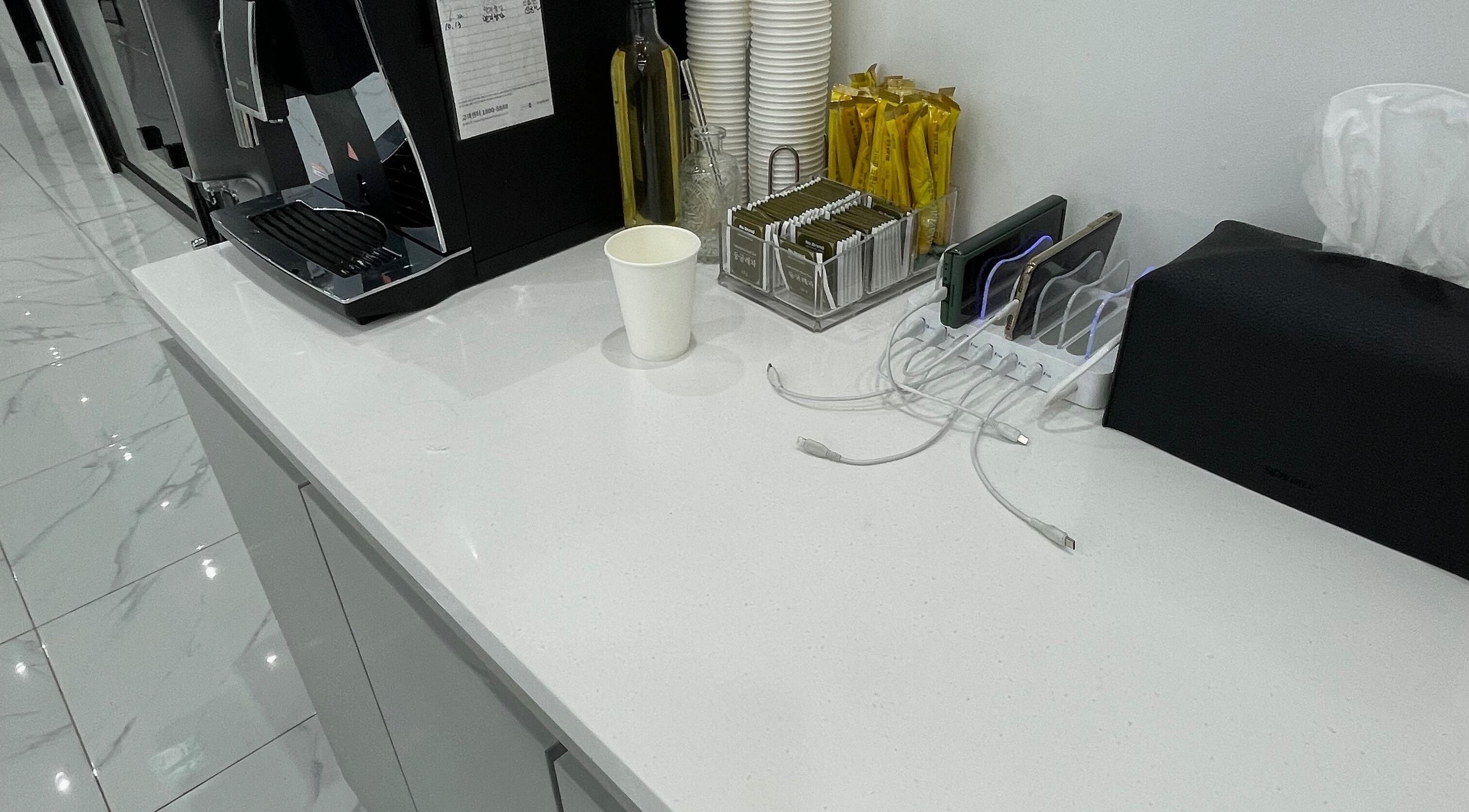 Sleek refreshment station at urGlow, Seoul, Seoul, KR with coffee setup and phone charging.