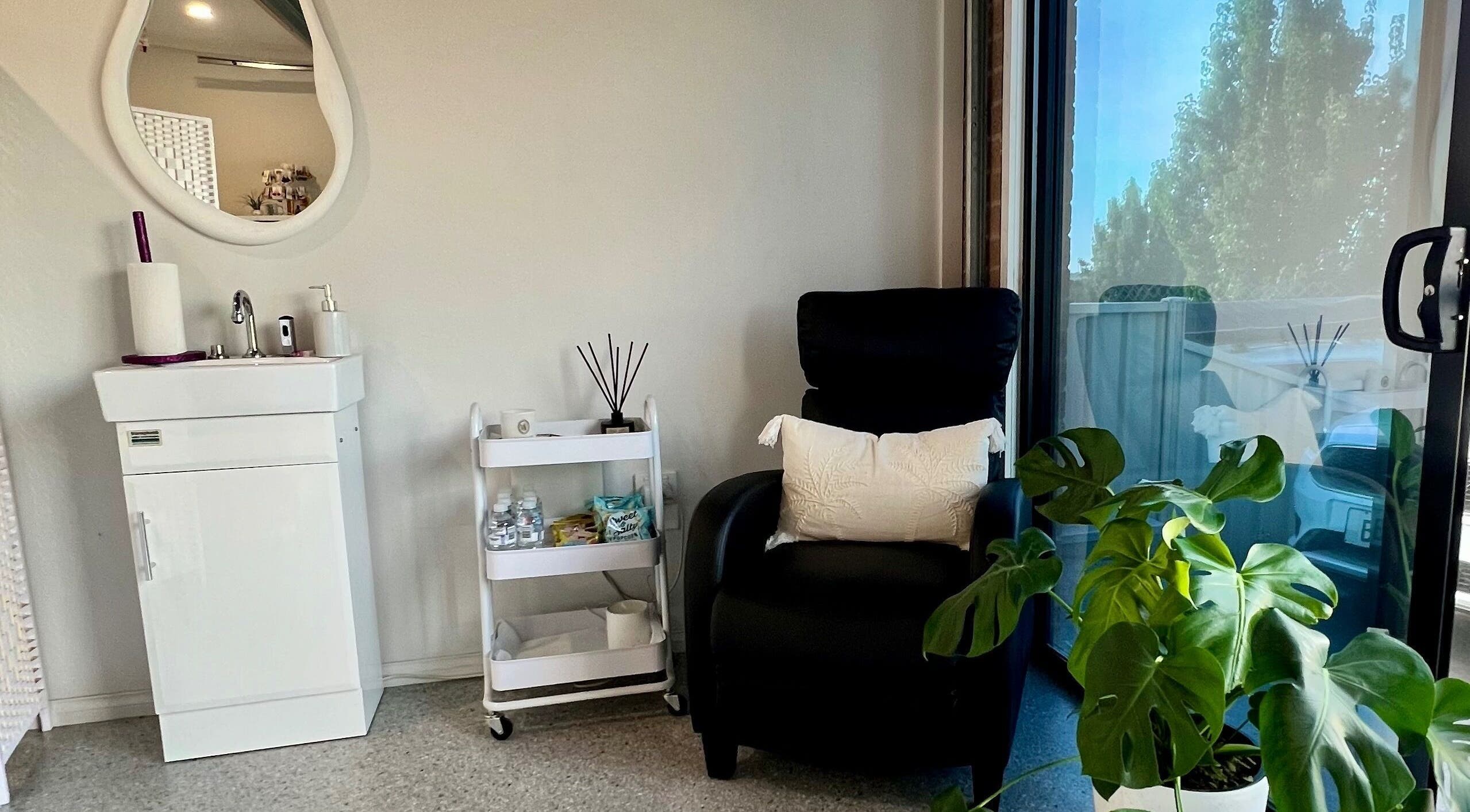 Relaxing corner at Bare Faced Beauty, Strath Creek, Victoria, AU with a chair, plant, and sink.