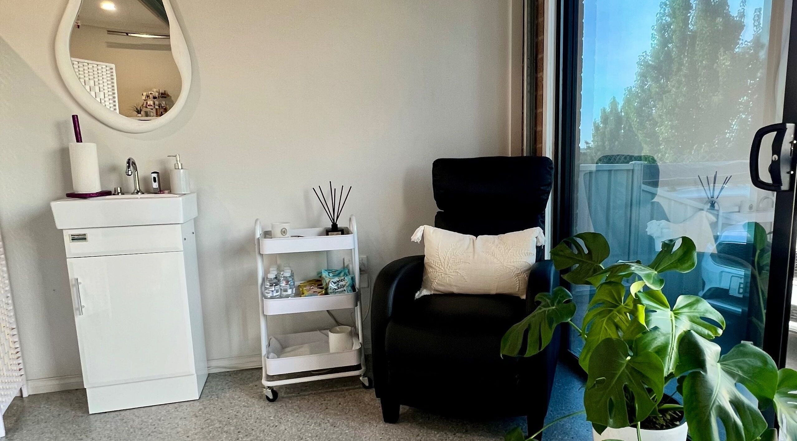 Relaxing corner at Bare Faced Beauty, Strath Creek, Victoria, AU with a chair, plant, and sink.