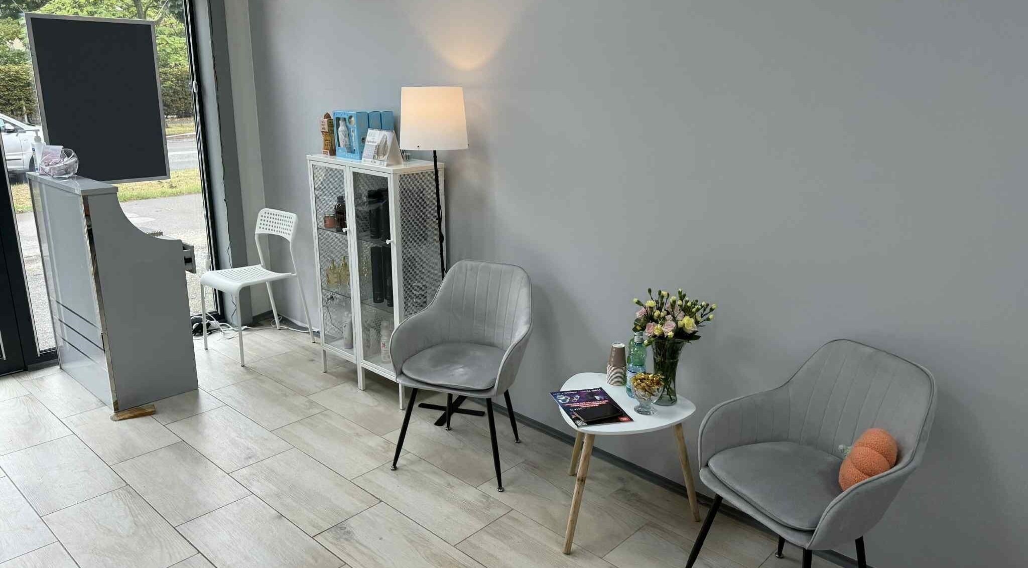 Elegancki kącik relaksu w Włos Love, Częstochowa, Województwo Śląskie, PL, z szarymi fotelami i bukietem.