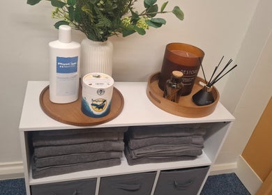 Essentials at Revive Sports Therapy And Massage in York, England, GB include lotions, candles, and neatly stacked towels.