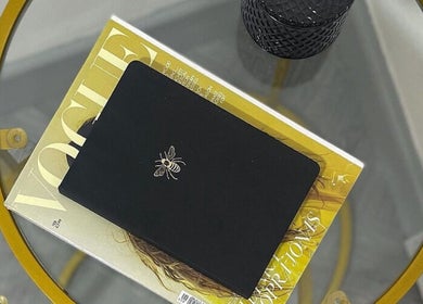 A chic tabletop at Leia Beth Lash & Brow Technician, Dundee, Scotland, GB featuring a magazine and a bee-embossed notebook.