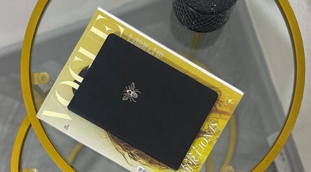 A chic tabletop at Leia Beth Lash & Brow Technician, Dundee, Scotland, GB featuring a magazine and a bee-embossed notebook.