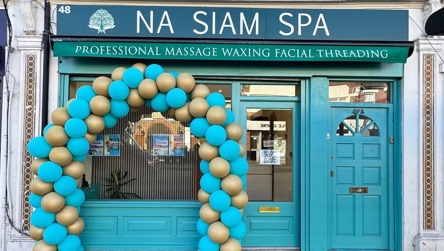 Elegant facade of Na Siam Spa in London, England, GB, with a stylish balloon arch and teal door.