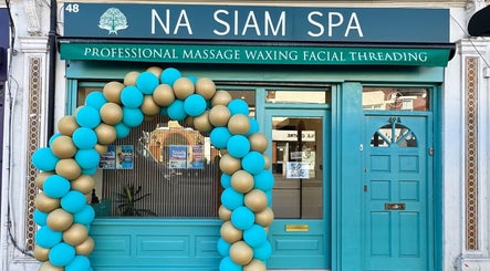 Elegant facade of Na Siam Spa in London, England, GB, with a stylish balloon arch and teal door.