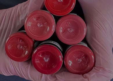 Red nail polish bottles held by a gloved hand at Tabitha Tweaks, Skelmersdale, England, GB.