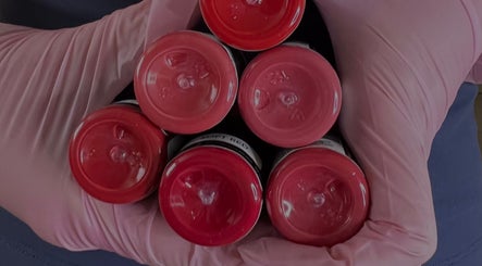 Red nail polish bottles held by a gloved hand at Tabitha Tweaks, Skelmersdale, England, GB.
