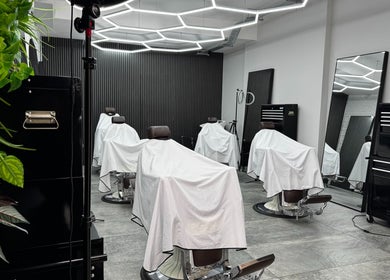 Modern barbershop interior at Barberesso, London, England, GB, featuring sleek barber chairs and bright lighting.