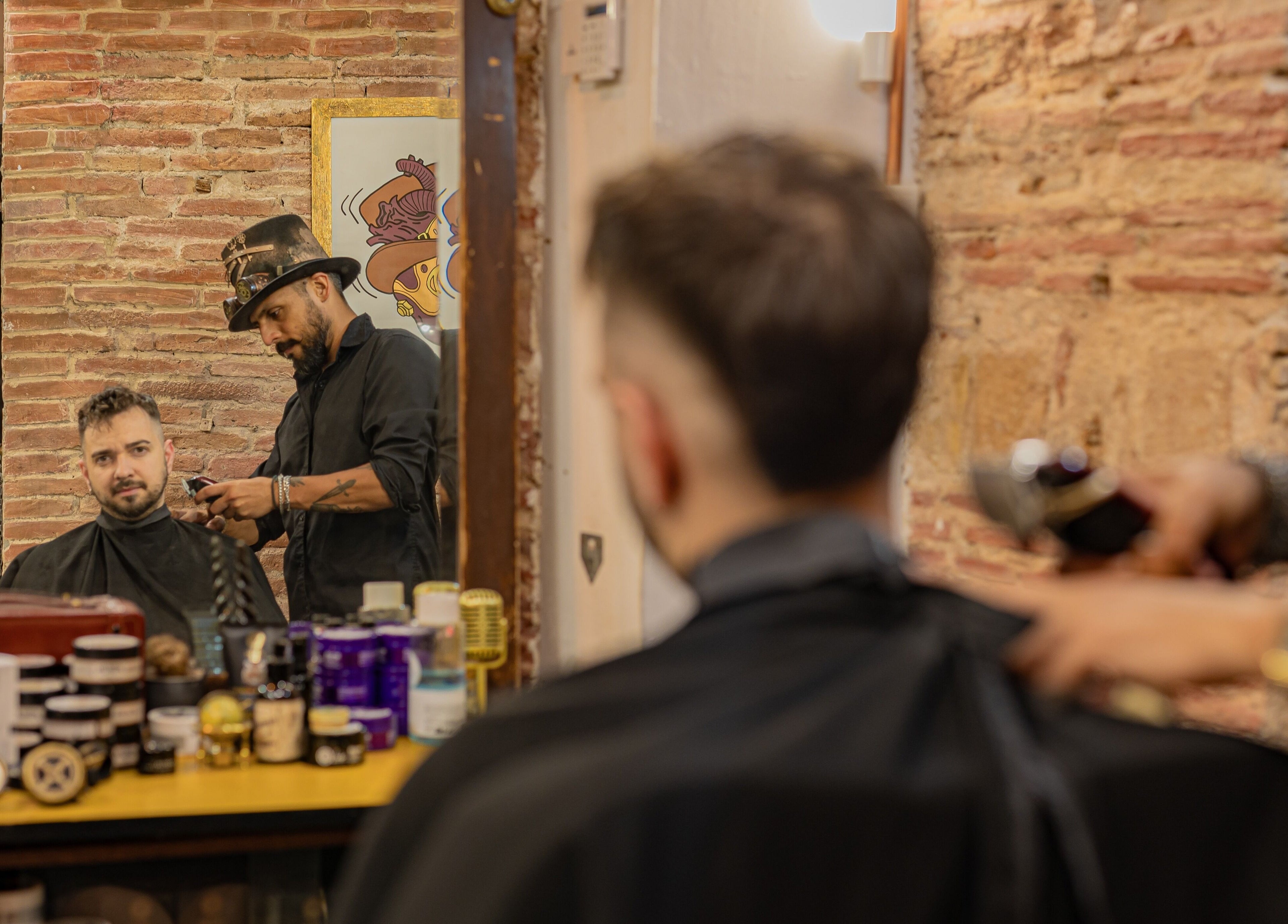 Mr. Braz Steampunk Barbershop en Barcelona, Catalunya, ES. Peluquero con sombrero cortando cabello.