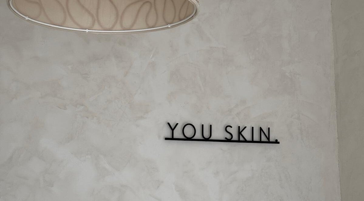 Mur minimaliste avec message 'You Skin' chez Joïa Piercings, Lyon, Auvergne-Rhône-Alpes, FR.