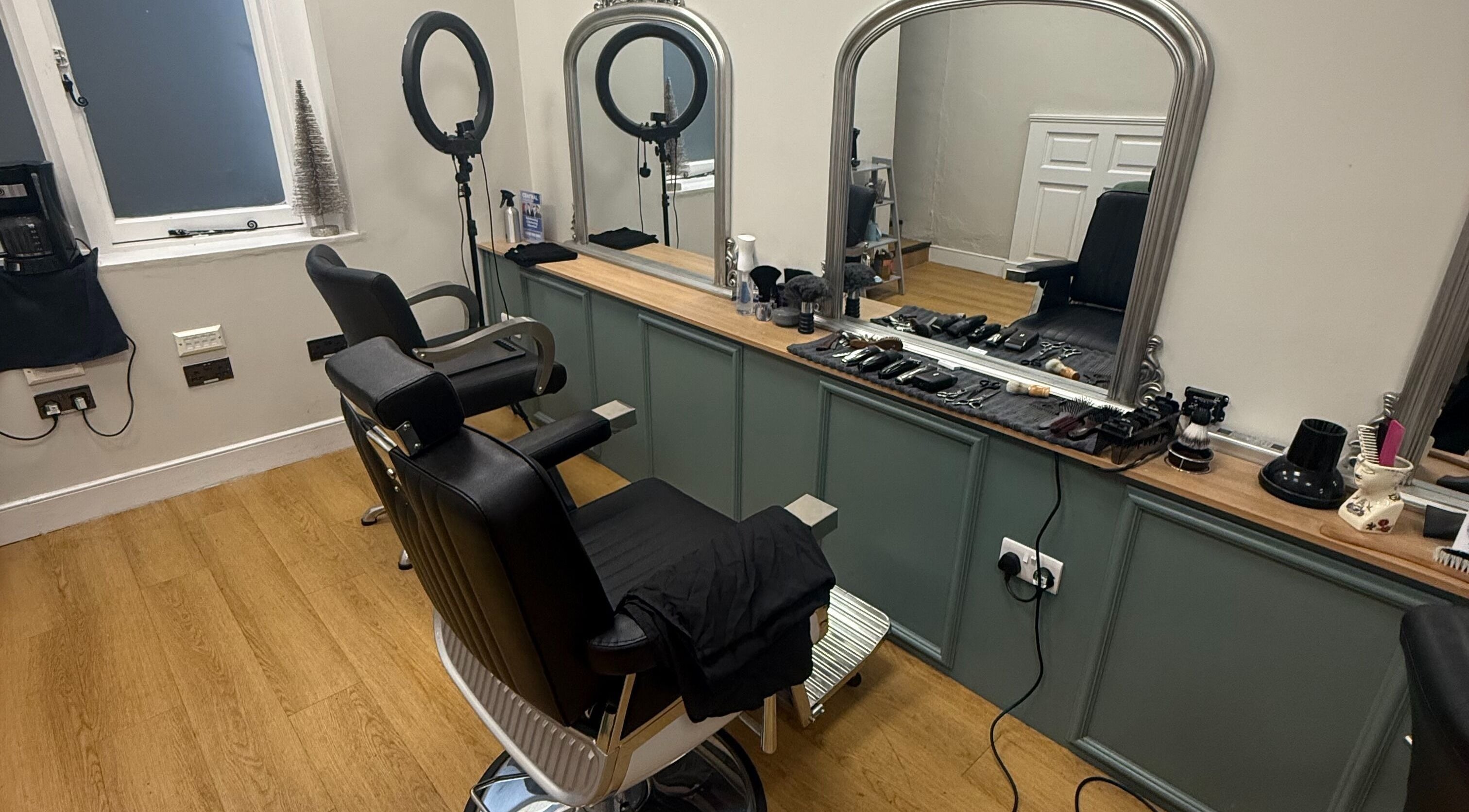 Modern salon interior at Cutthroat & Hound (the Archway), Aylesbury, England, GB, featuring sleek barber chairs.