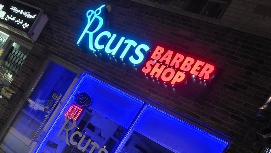 RCutsBarberShop neon sign glows vibrantly at night in Hamilton, Ontario, CA.