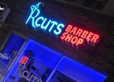 RCutsBarberShop neon sign glows vibrantly at night in Hamilton, Ontario, CA.