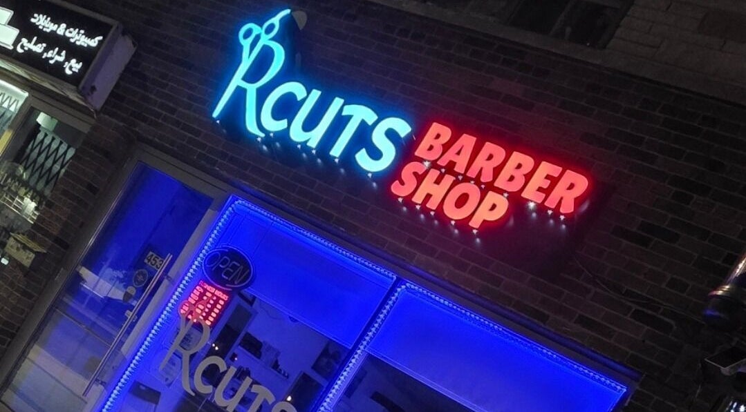 RCutsBarberShop neon sign glows vibrantly at night in Hamilton, Ontario, CA.