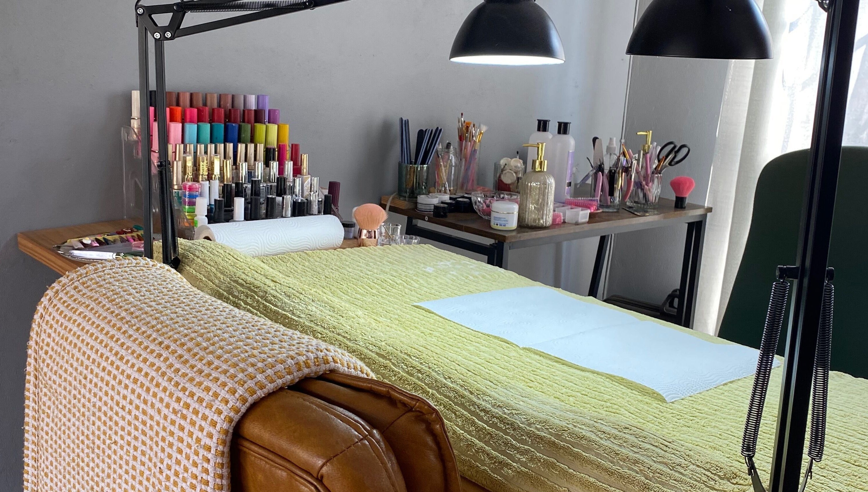 Bright, inviting nail station at Clawed._ in Akasia, Gauteng, ZA with colorful polishes and cozy chair.