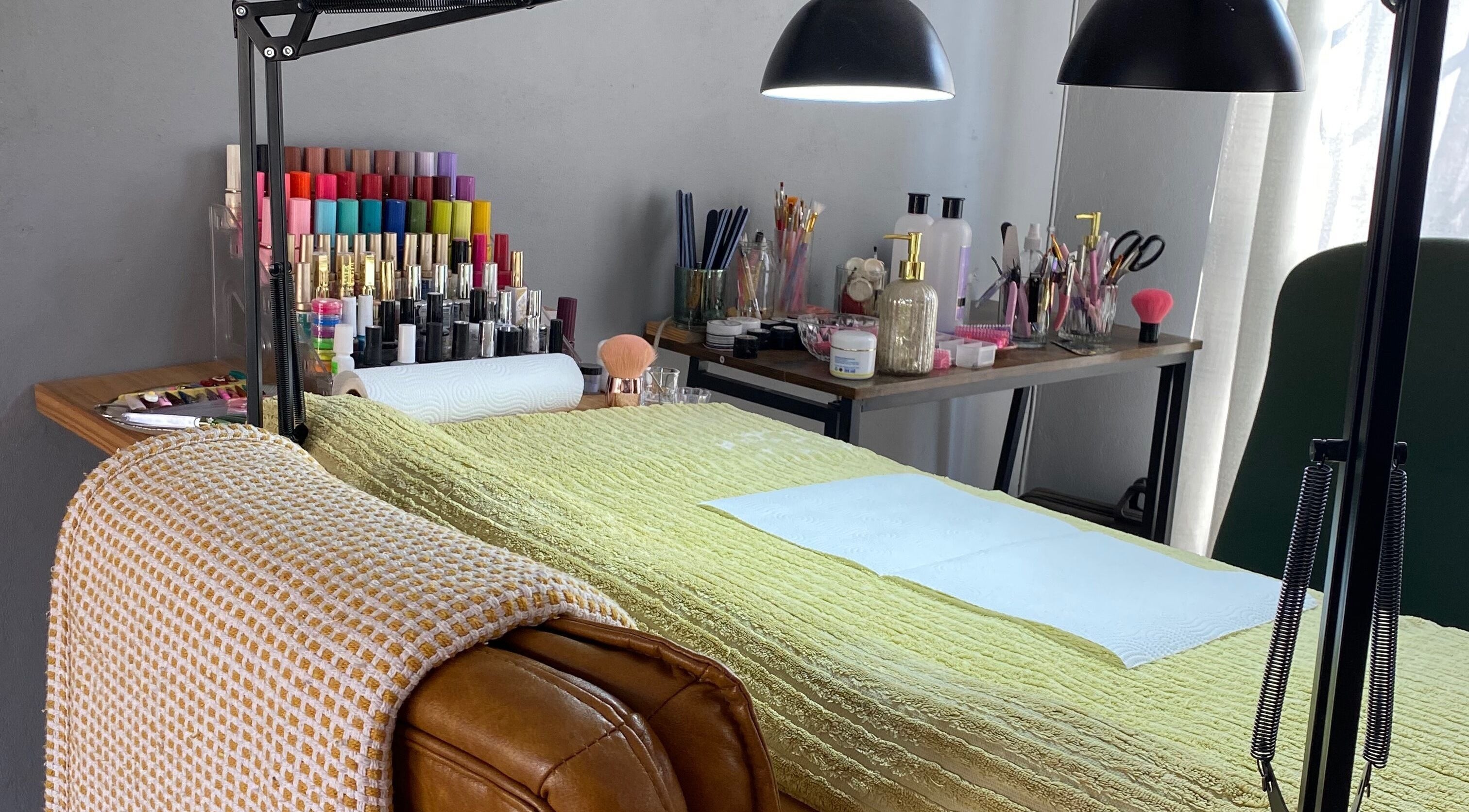 Bright, inviting nail station at Clawed._ in Akasia, Gauteng, ZA with colorful polishes and cozy chair.