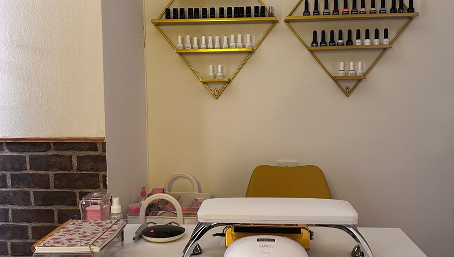 Estación de manicura en Aura Esthetics, Huelva, Andalucía, ES, con esmaltes y silla amarilla.