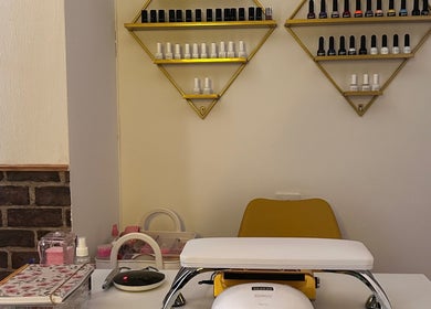 Estación de manicura en Aura Esthetics, Huelva, Andalucía, ES, con esmaltes y silla amarilla.