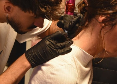 Tattoo-artiest werkt aan nekdesign bij Visualex, Oosterzele, Vlaanderen, BE.