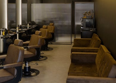 Elegant interior of Brocave Groomers in Dubai, Dubai, AE, featuring plush brown chairs and sleek styling stations.
