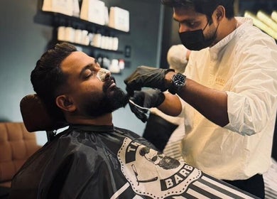 A stylist trims a man's beard at Brocave Groomers, Dubai, Dubai, AE, showcasing expert grooming services.