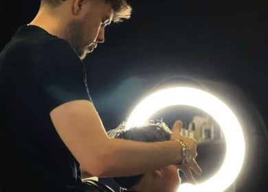 Coiffeur à Dryann Barber à Caen, Normandie, FR, stylant les cheveux sous une lumière circulaire moderne.