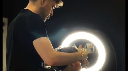 Coiffeur à Dryann Barber à Caen, Normandie, FR, stylant les cheveux sous une lumière circulaire moderne.