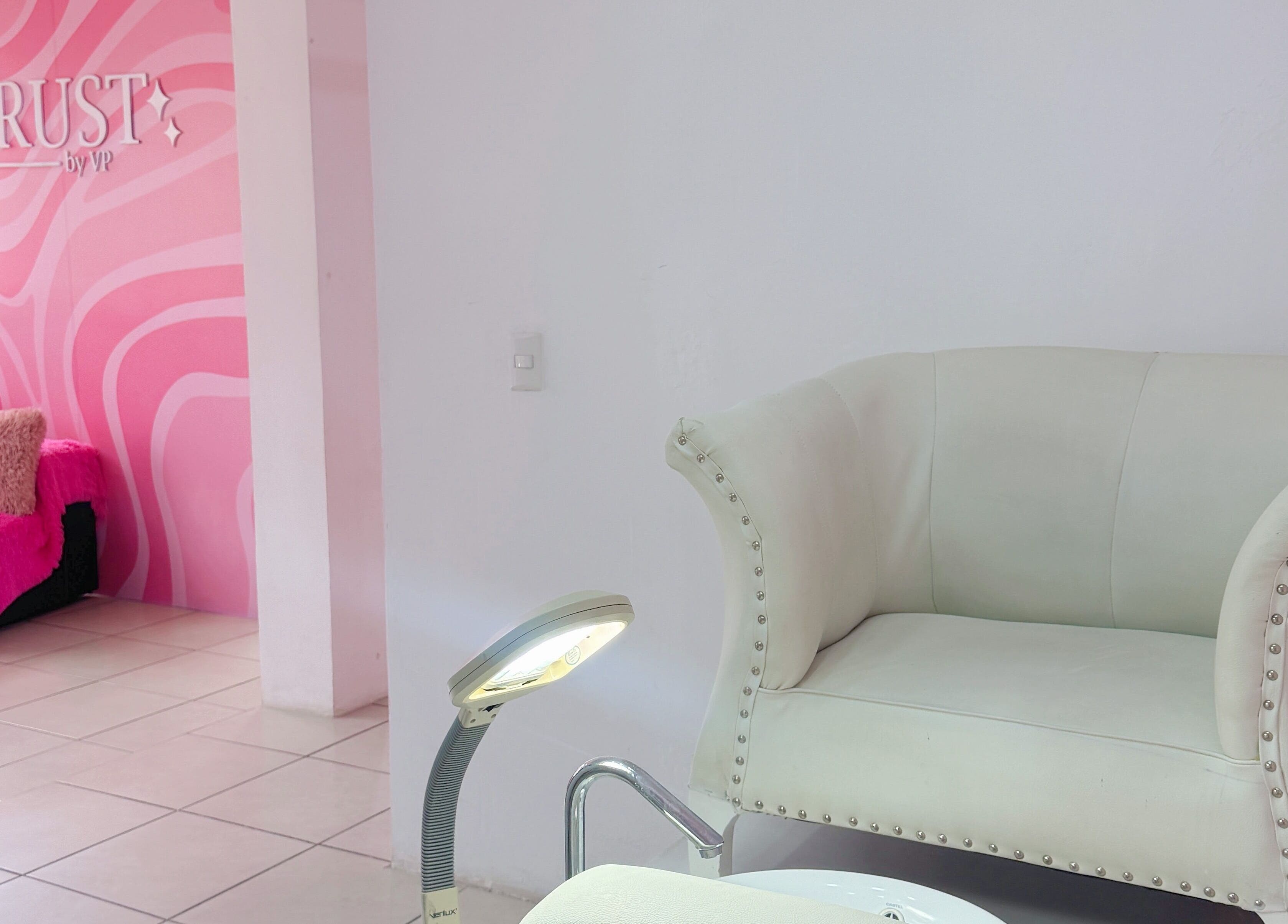 Área de descanso con sillón blanco y decoración rosa en TRUST, Quetzaltenango, Quetzaltenango, GT.