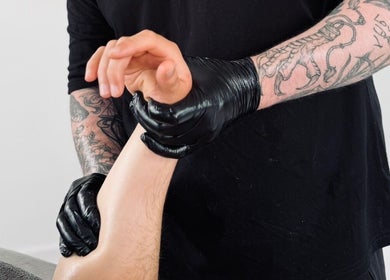 Therapist at Dan Orchard Sports Massage, Exeter, England, GB performing a forearm massage in black gloves.